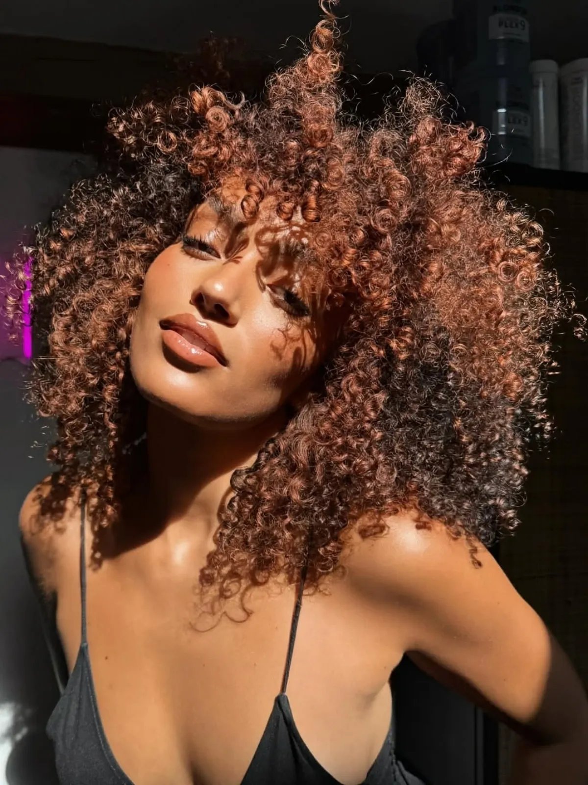 Model with cinnamon mocha brown curls featuring warm copper highlights for a vibrant, dimensional effect.
