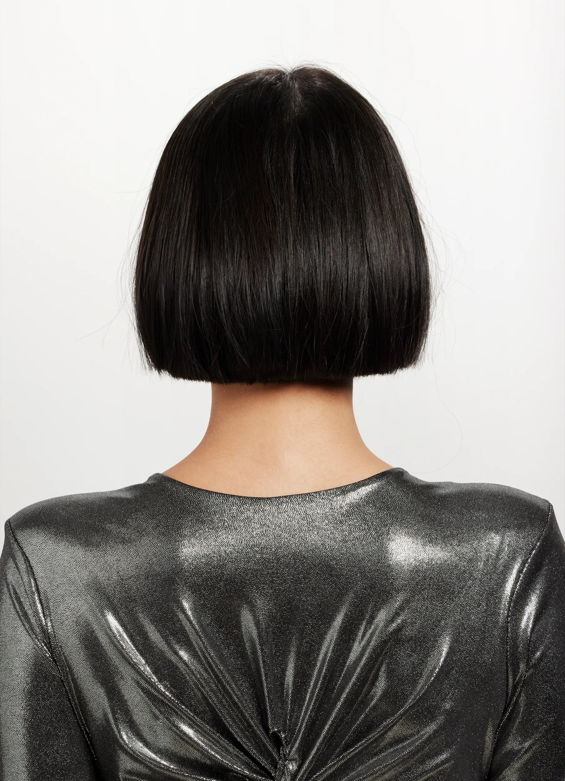 Before image of a woman's hair from the back, sporting a black short bob. 
