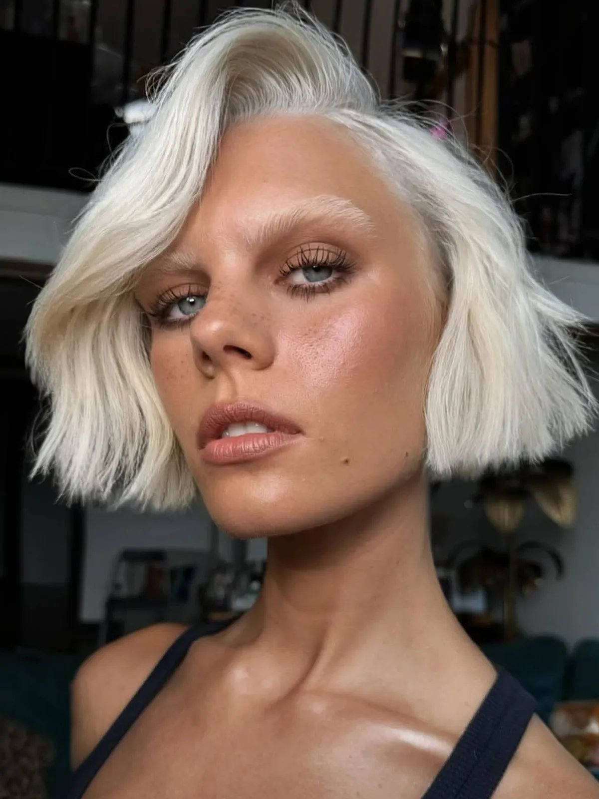 Model with white blonde micro bob swept to one side.
