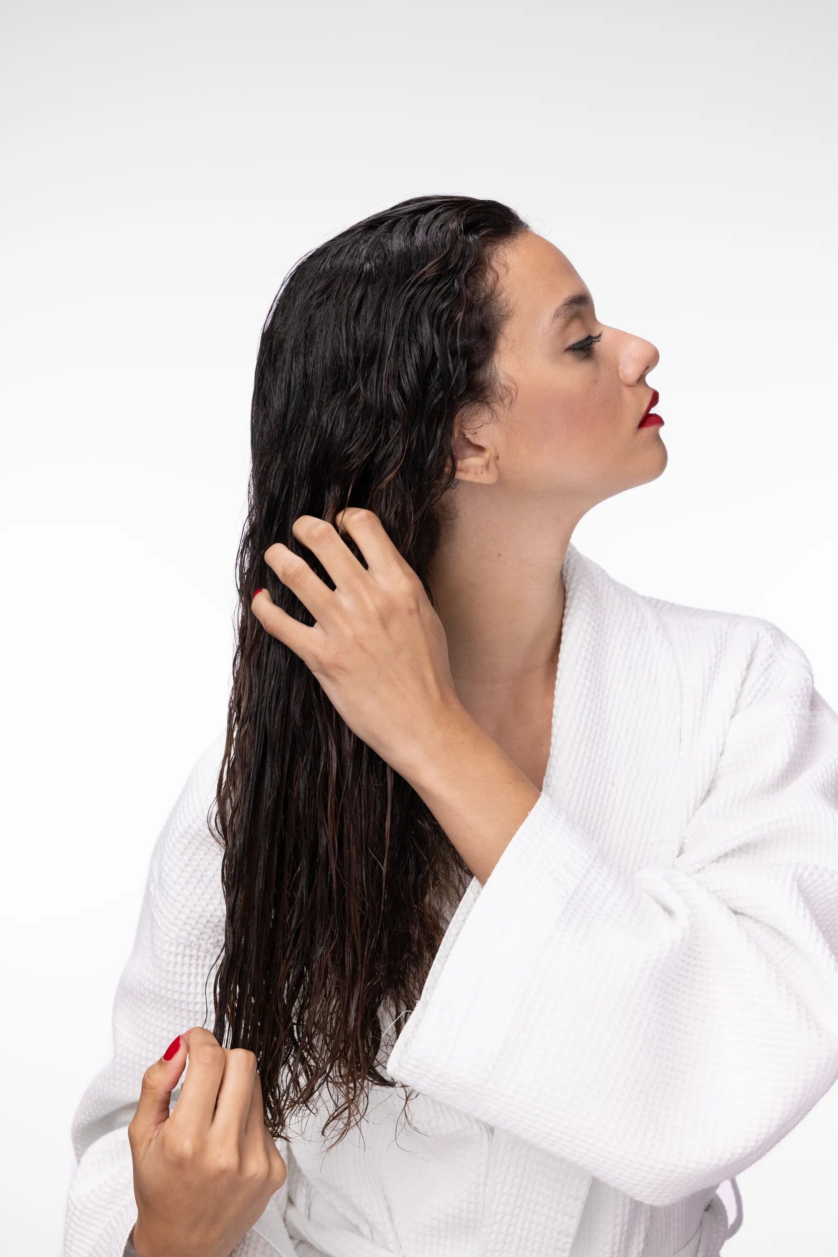 Model wearing a robe runs fingers through long, wavy, brunette hair.