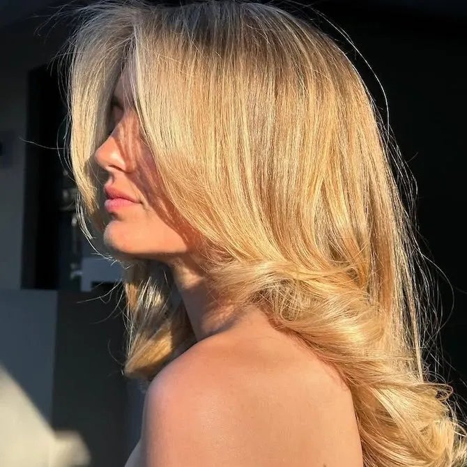 Sun shines on model’s honey blonde, glossy hair. 