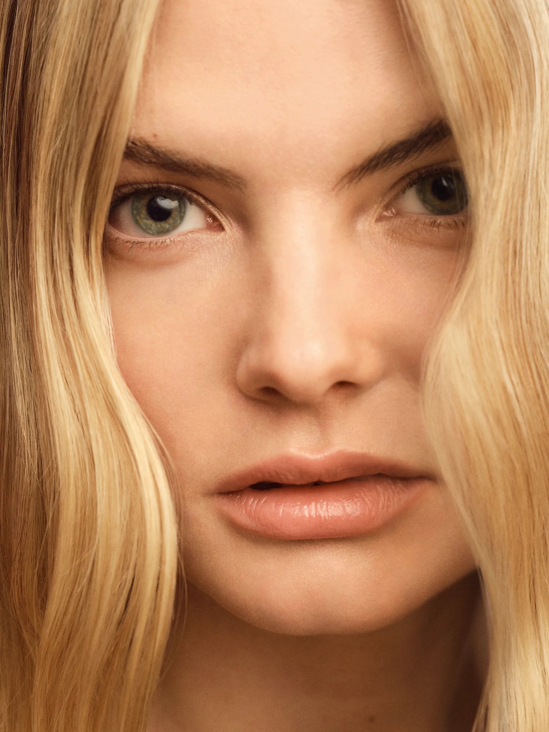 A model with blonde hair looks to the camera