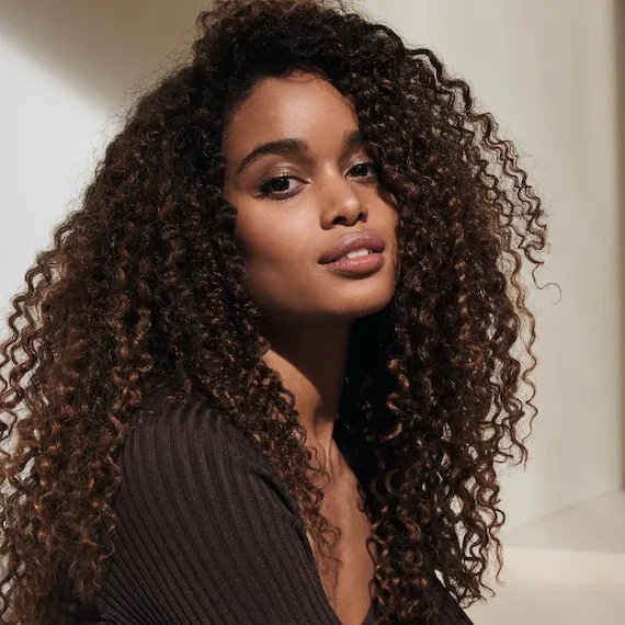 Close-up of a model with dark, curly hair covering their face.