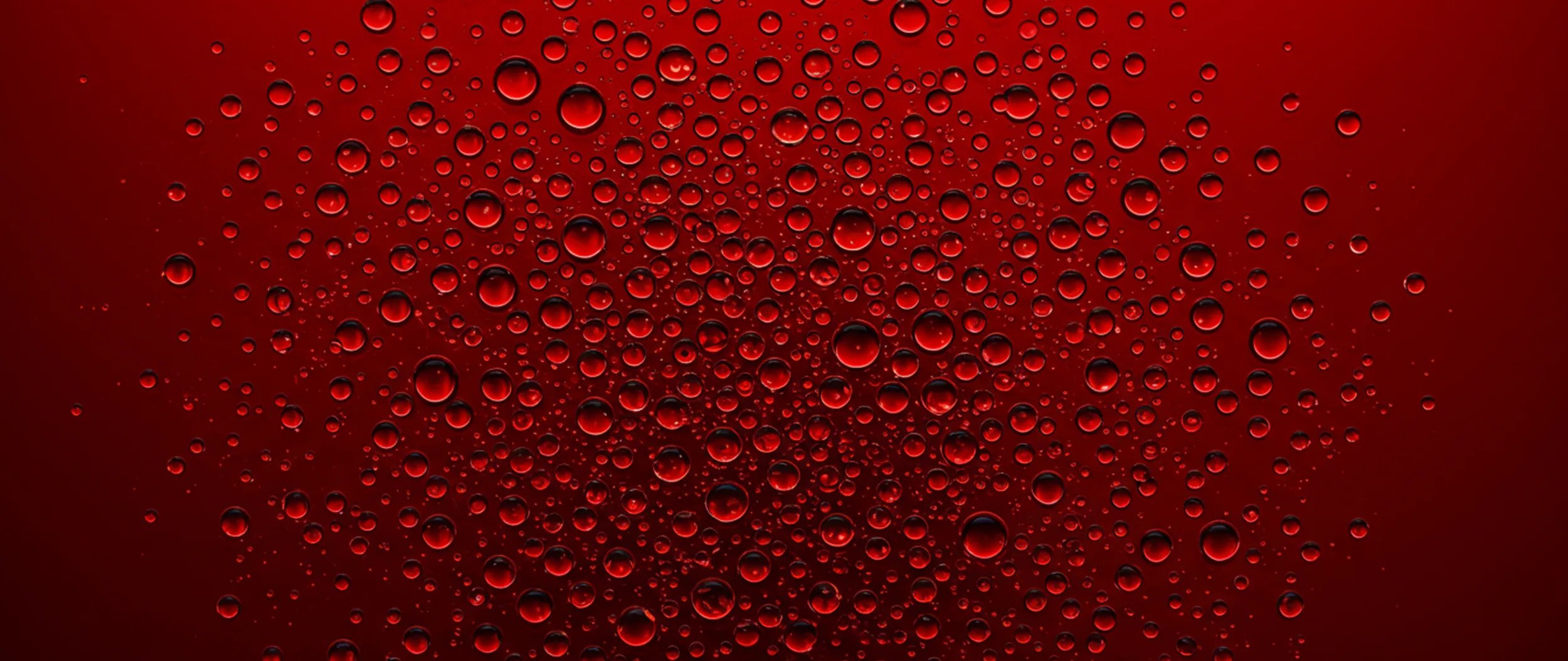 Close up of clear droplets against red background.