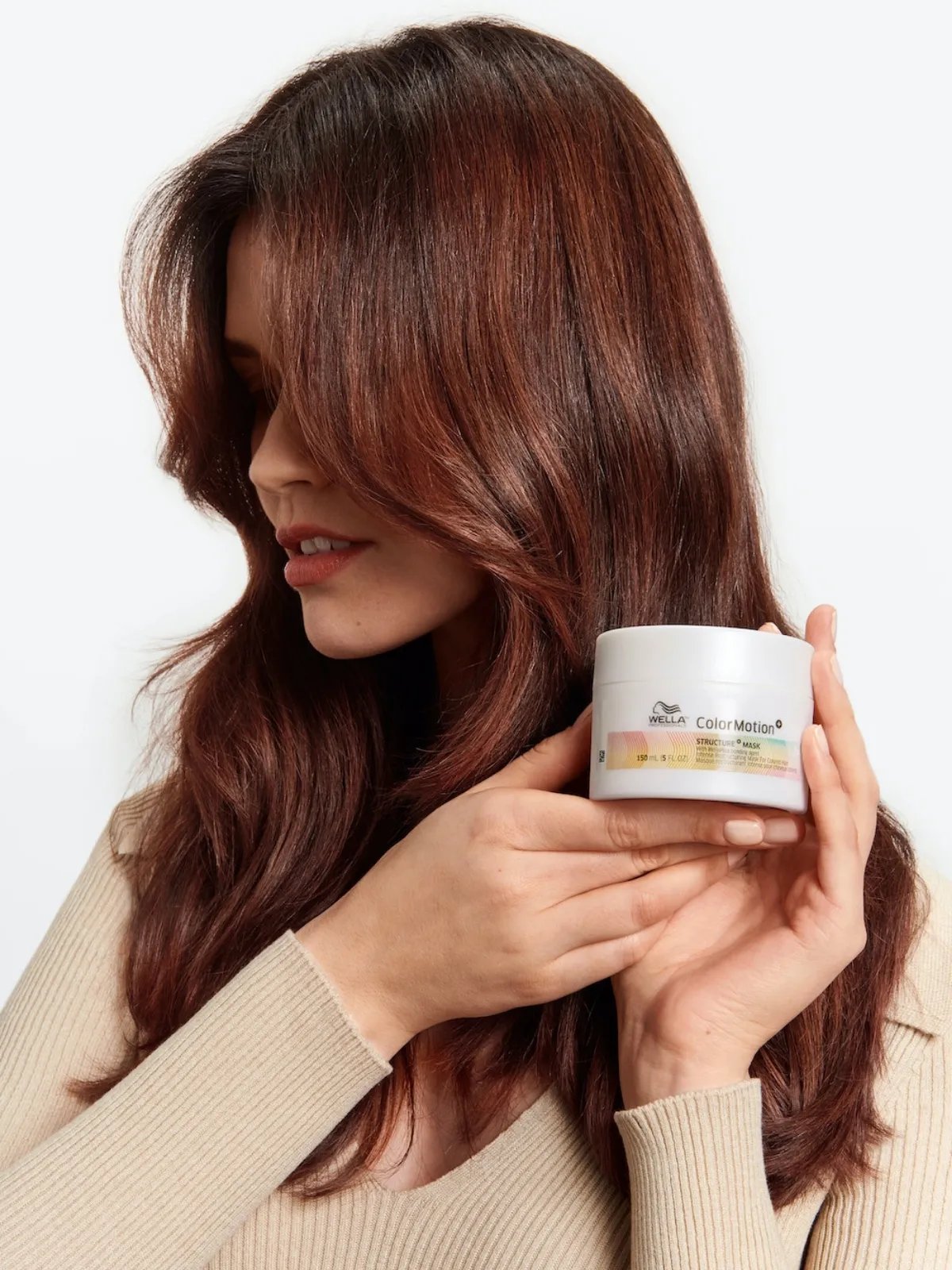 Model with strong, shiny, brunette hair holds a jar of ColorMotion+ Structure+ Mask.