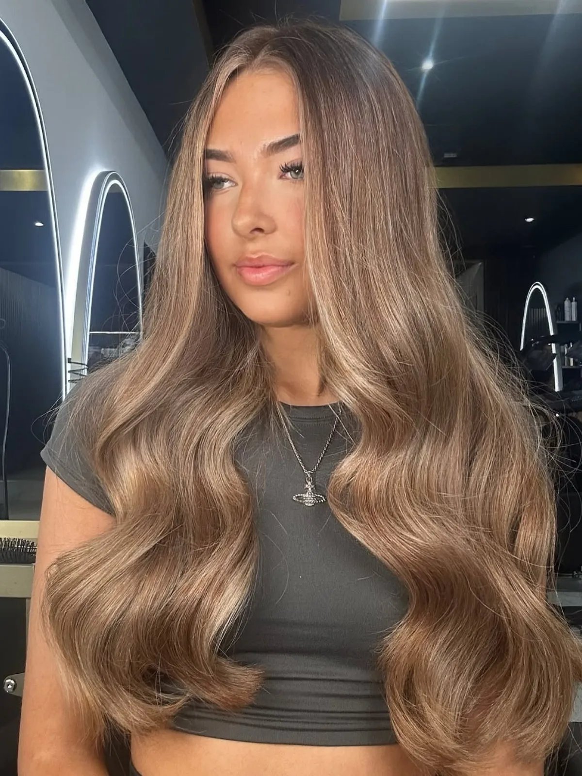 Model with long, loosely curled, neutral brown-blonde hair with a suede-like finish.