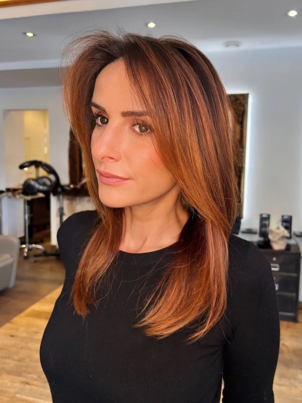 Model with mid-length, straight hair that’s dark at the roots and a burnished copper through the lengths.