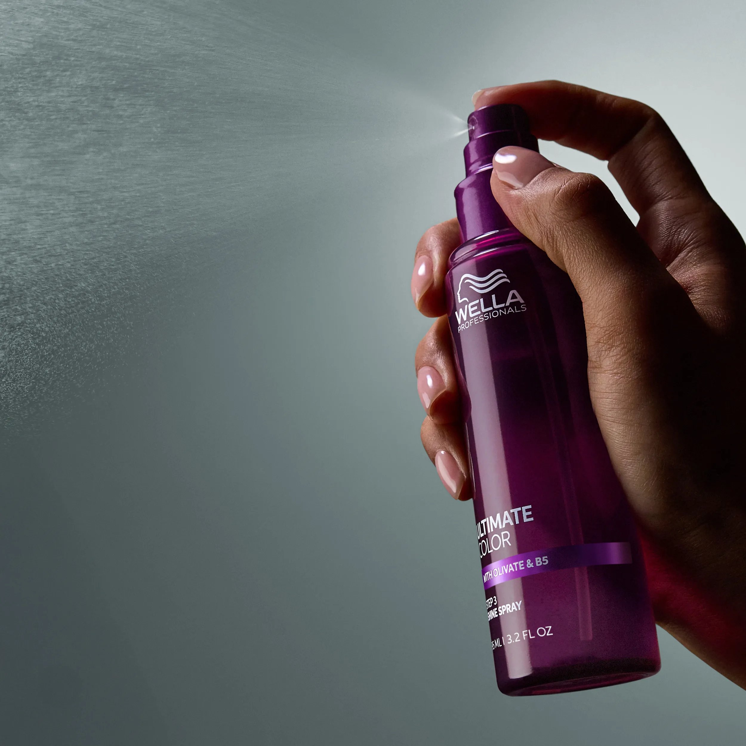 Image of model spraying the Ultimate Color shine spray. Text overlay reads "Mist to add shine and smoothness".