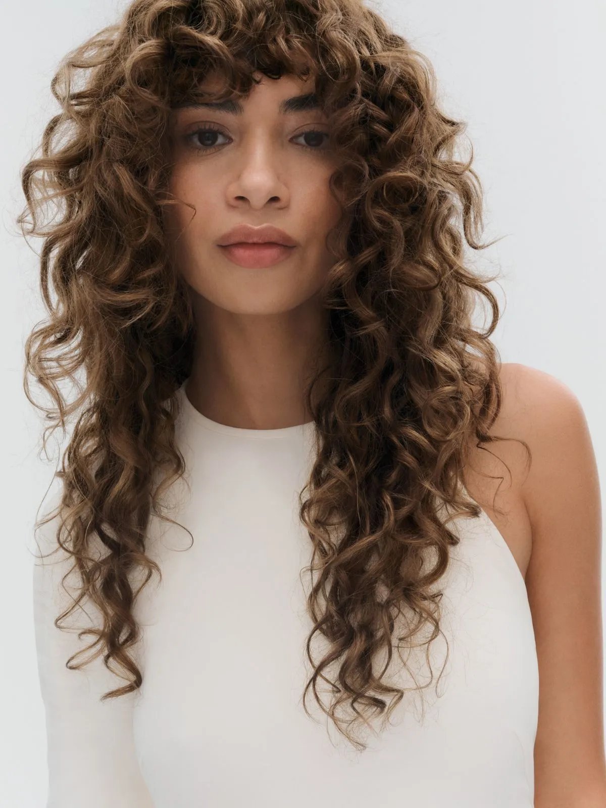 Model with long, curly, chocolate brown hair.
