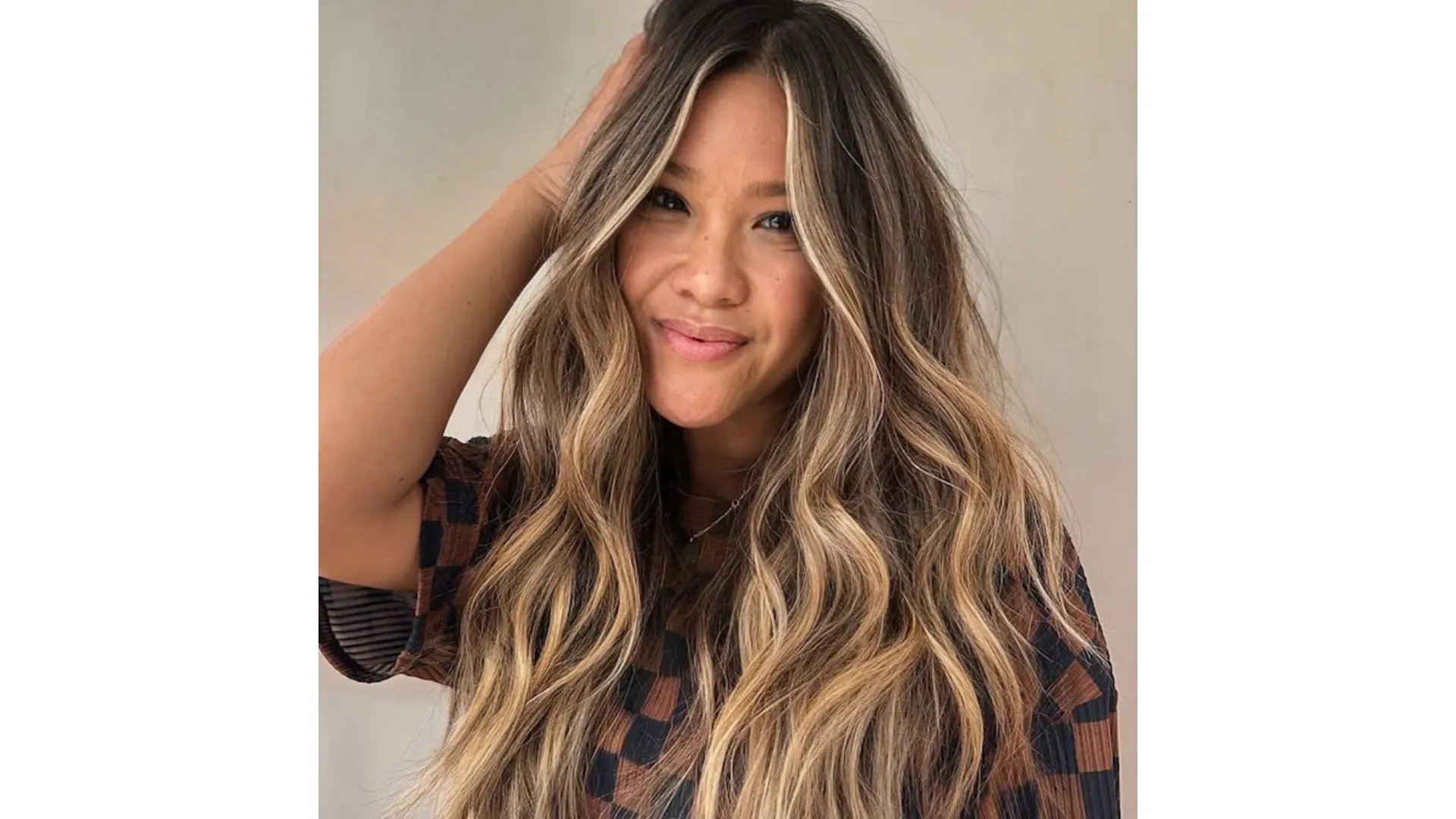 Model with long, wavy, hair featuring a dark brown root stretch and beachy blonde balayage.