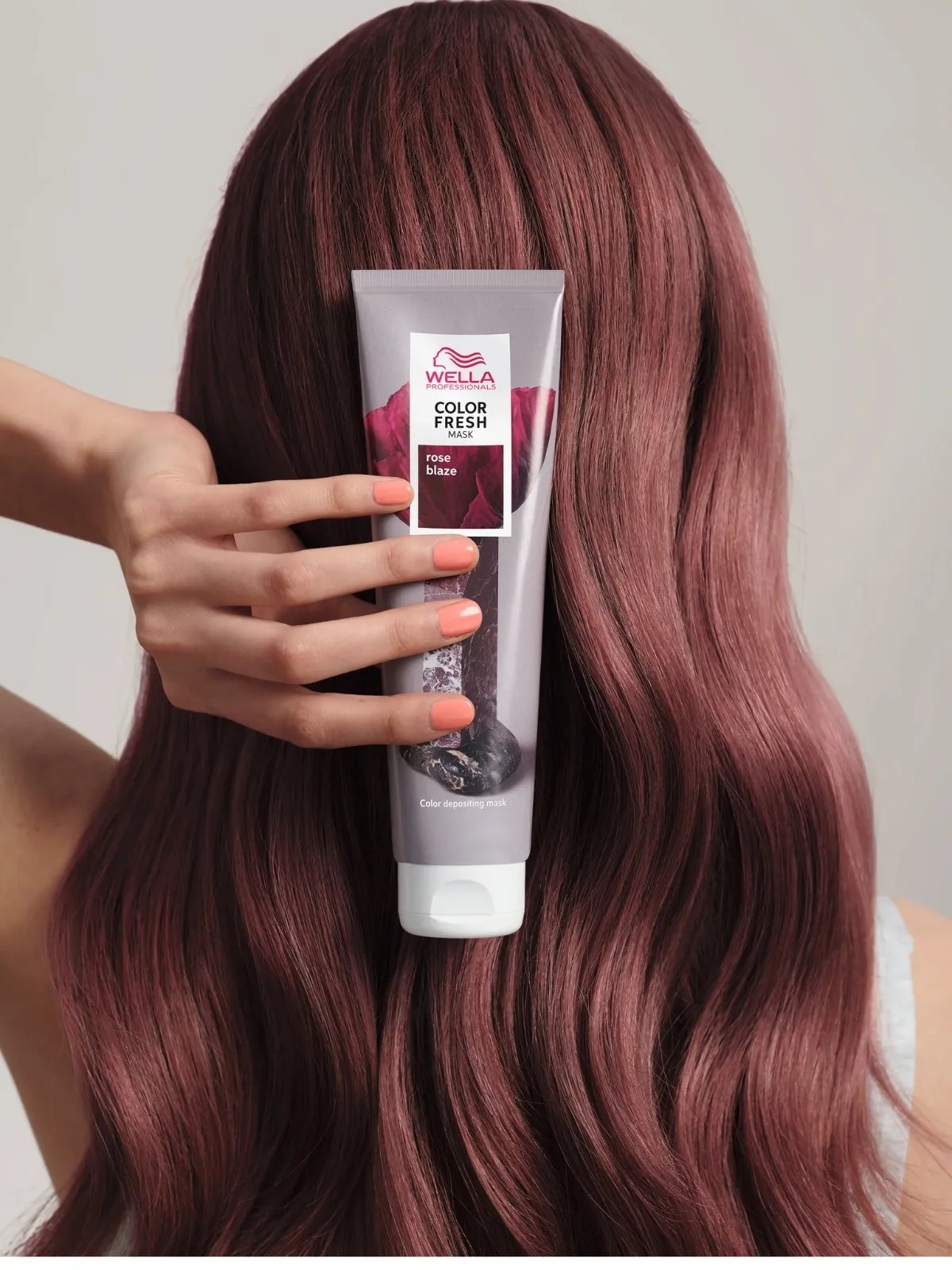 Model with rose brown hair holds up Color Fresh Mask in Rose Blaze.