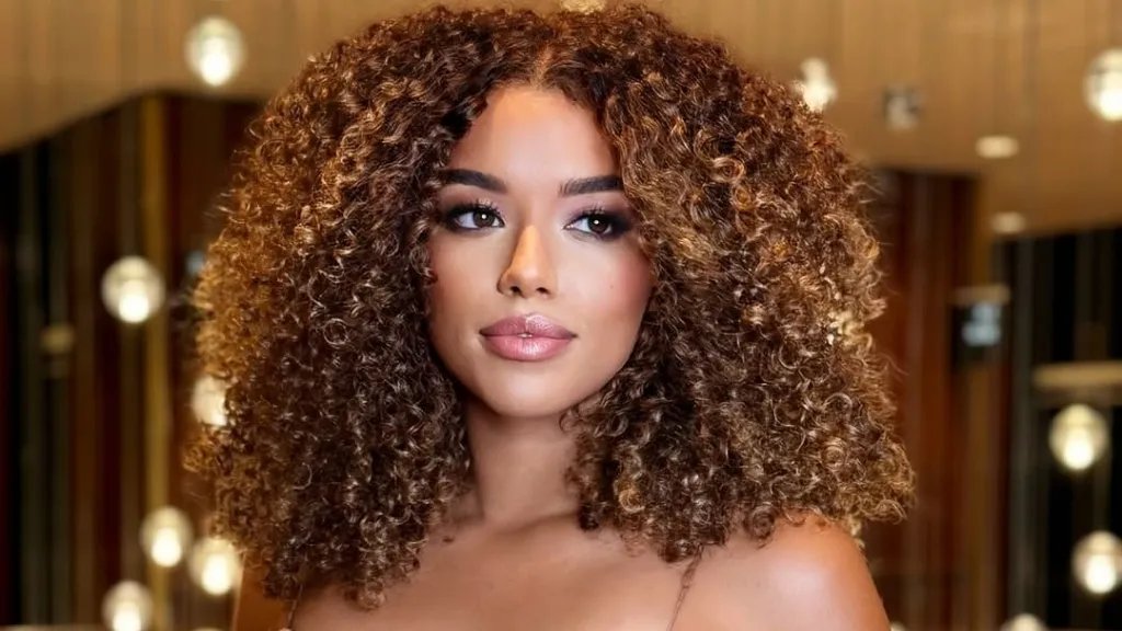 Model with curly, glossy, dark golden blonde hair.
