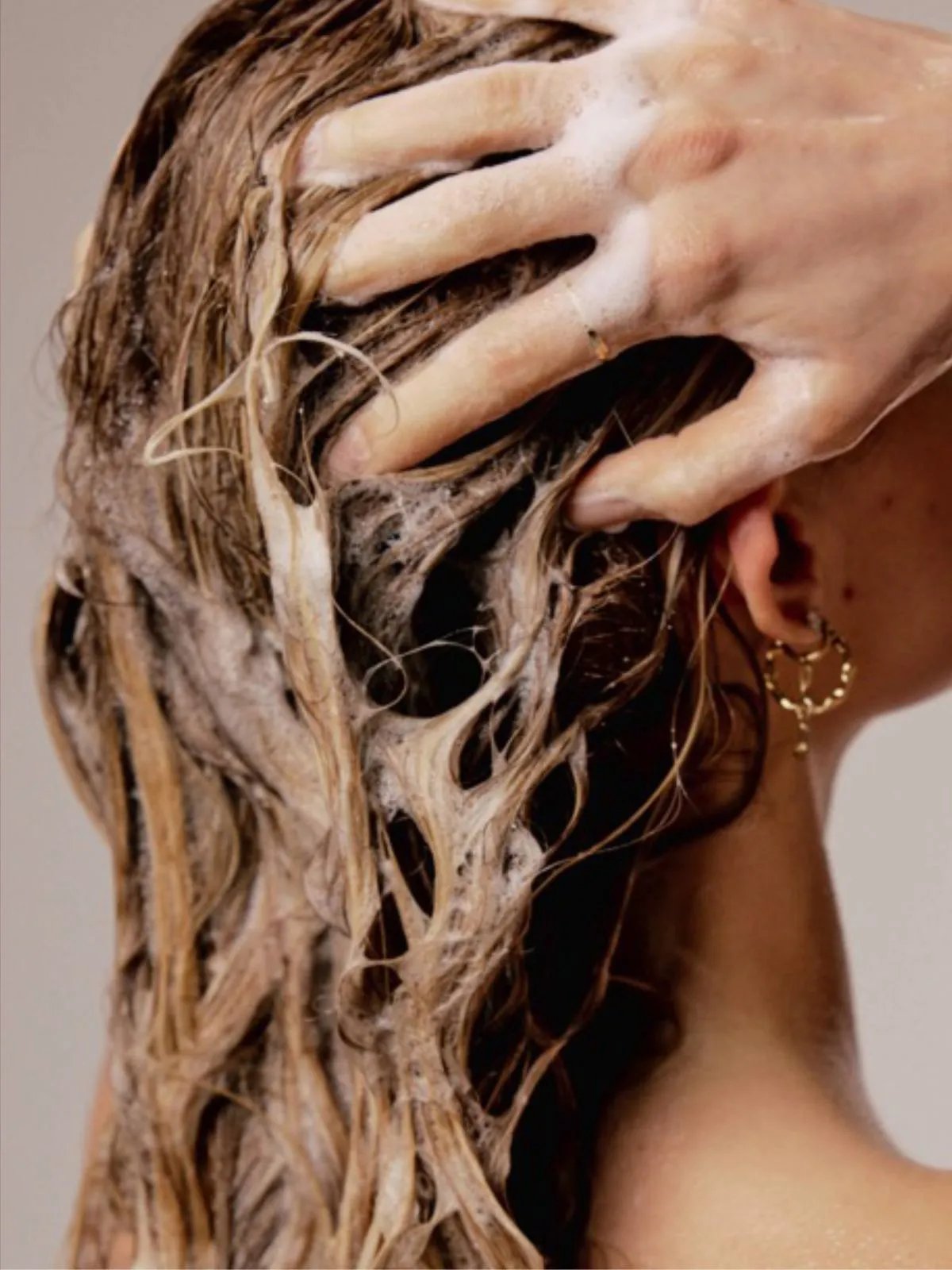 Model massages ULTIMATE REPAIR Shampoo into their wet hair.