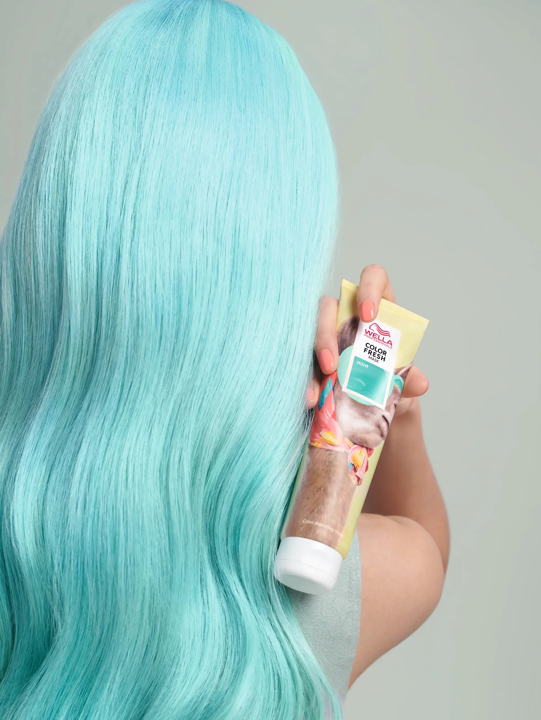 Rückansicht vom Kopf einer Frau, die eine Color Fresh Mask in der Hand hält.