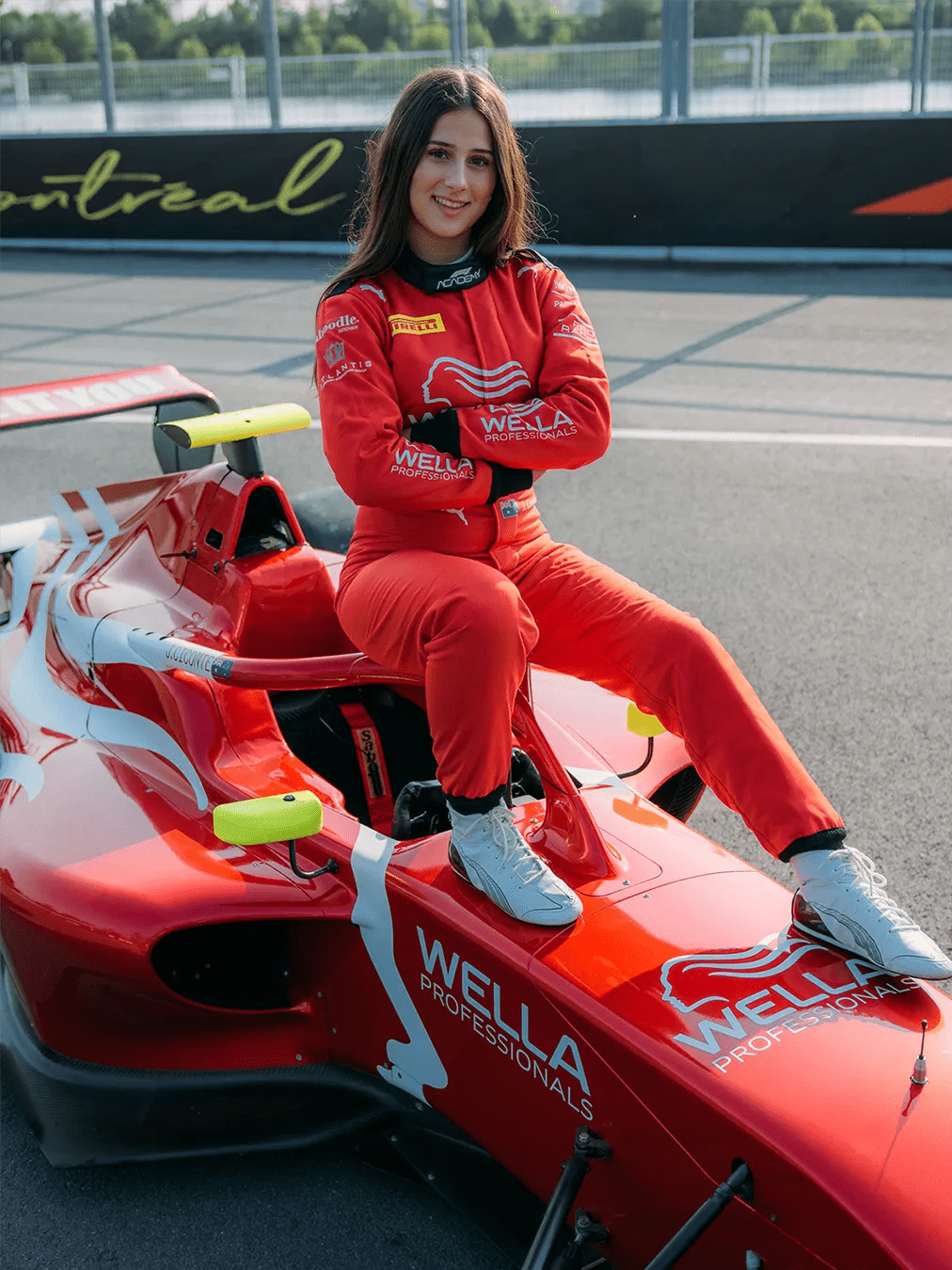 Joanne Ciconte from F1 Academy wearing a red Wella Professionals suit and car