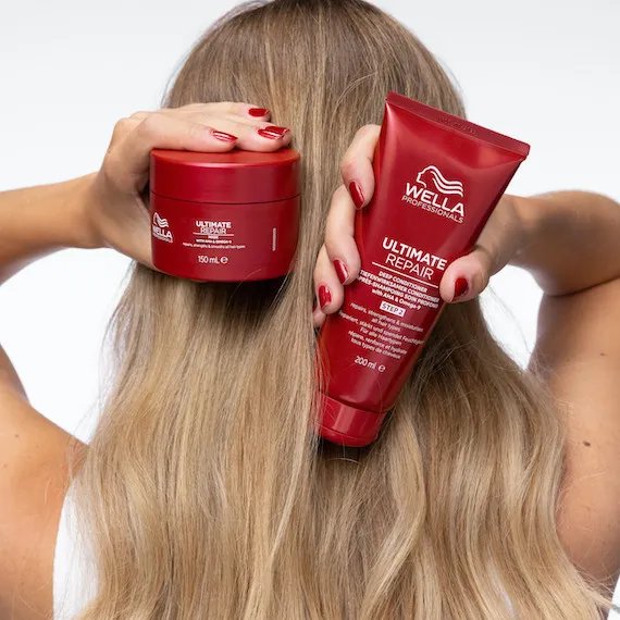 Back of model’s head with long, blonde hair. The model is holding up the ULTIMATE REPAIR Mask and ULTIMATE REPAIR Conditioner. 
