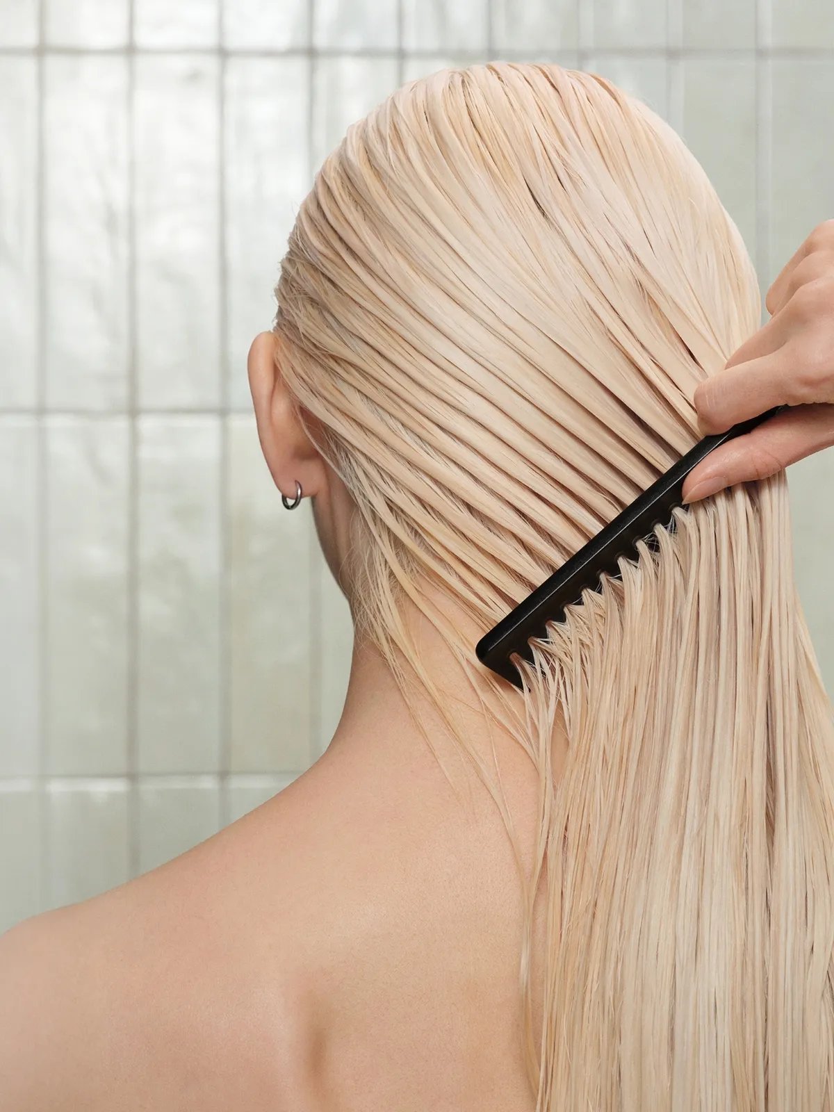 Model wearing a robe runs fingers through long, wavy, brunette hair.