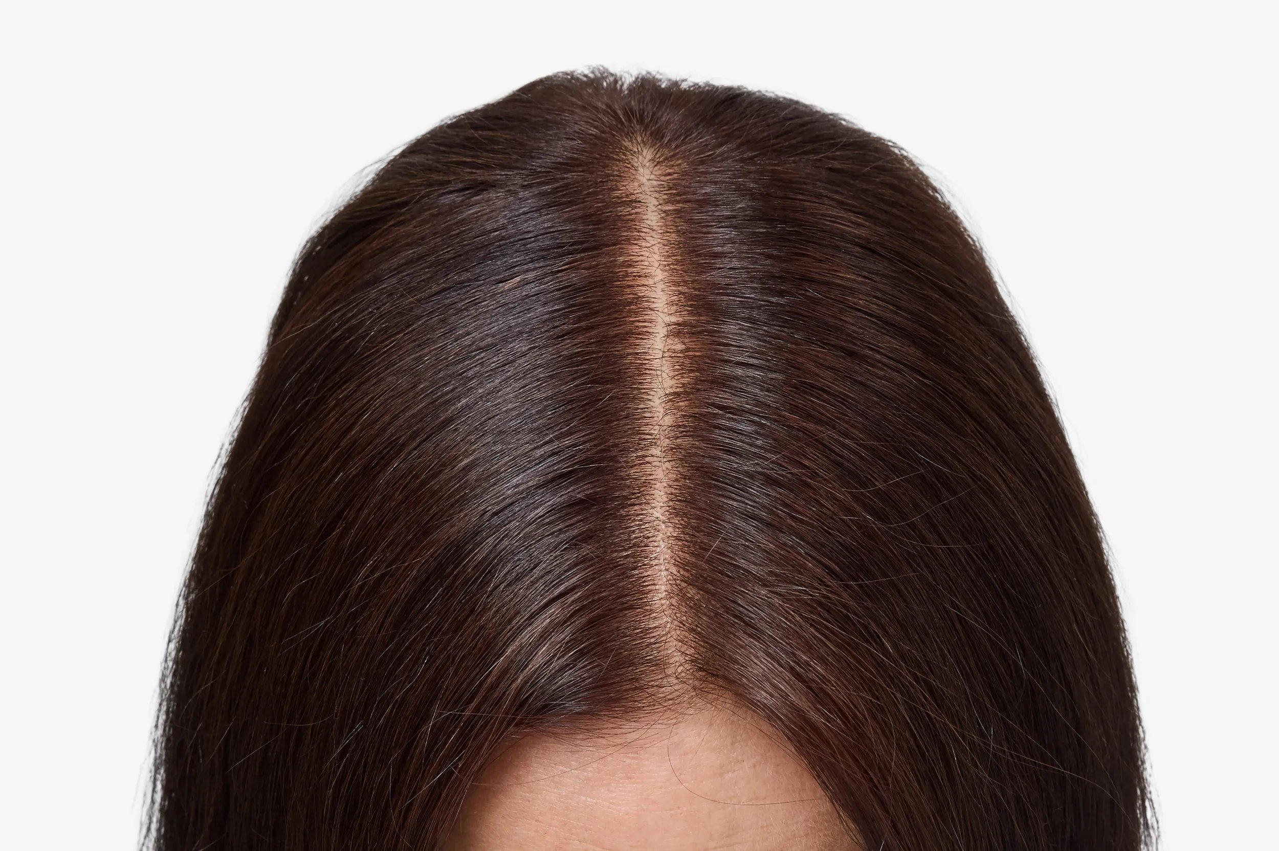 Close-up of model’s roots on dark brown hair.