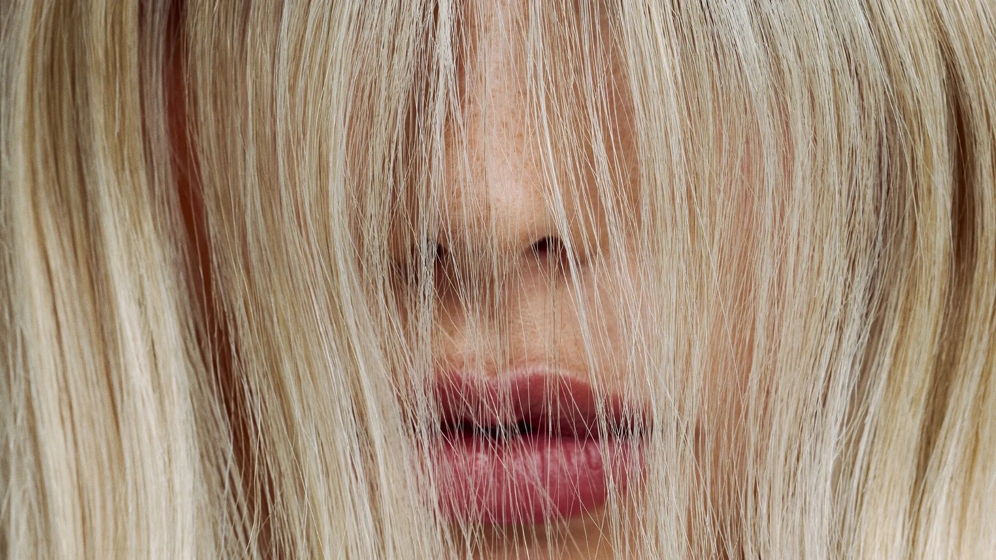 Close-up of blonde model with their hair covering their face.