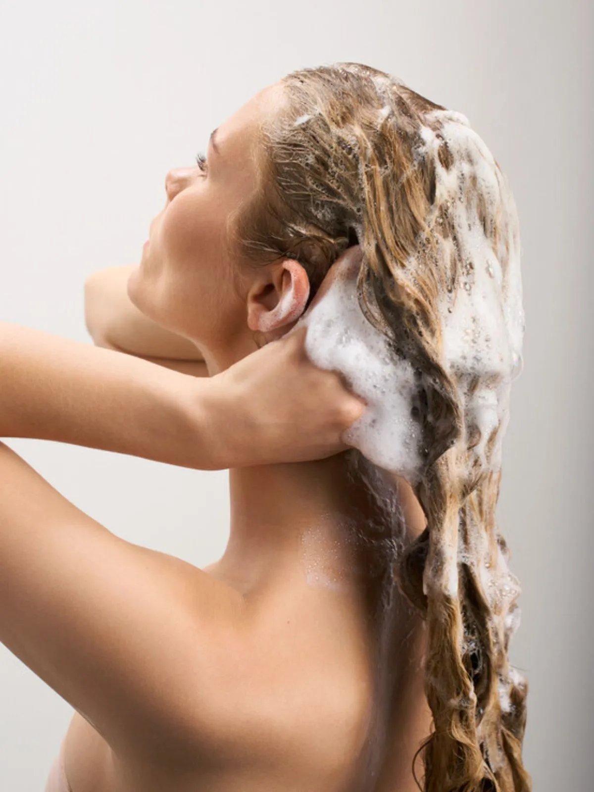 Model massages ULTIMATE SMOOTH Shampoo into their wet hair.