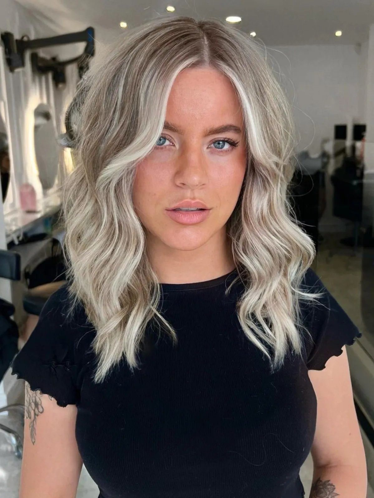 Model with platinum and ash blonde highlighted waves in a salon setting.
