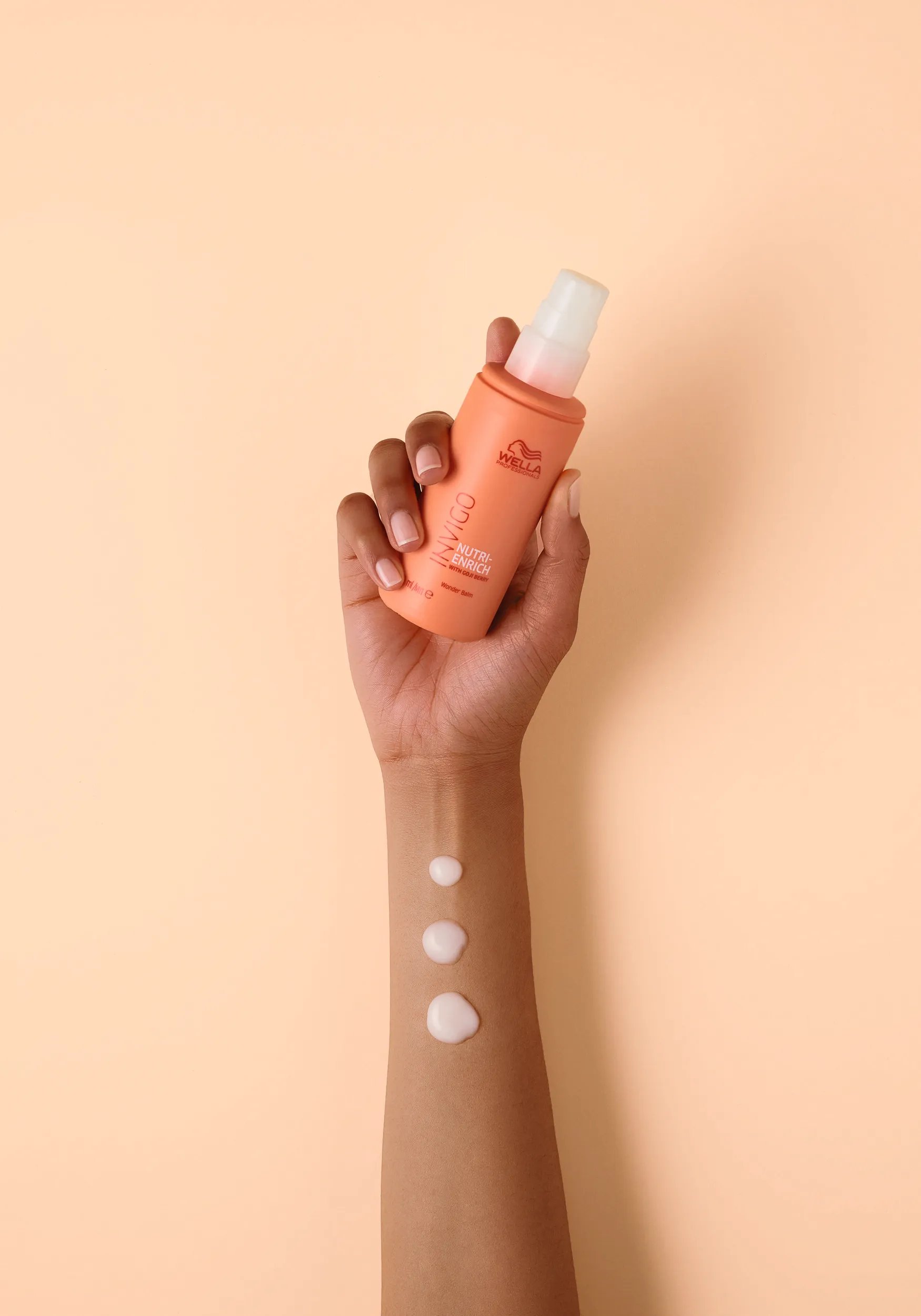 Hand holds up INVIGO Nutri-Enrich Wonder Balm.