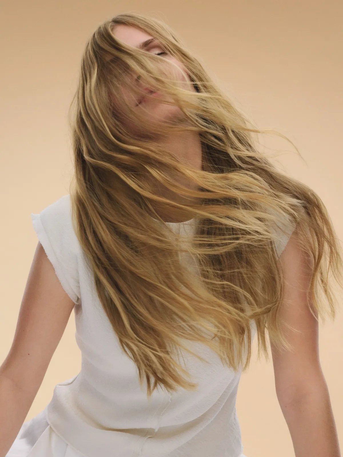 La modella fa ondeggiare i suoi lunghi capelli biondi, spettinati.