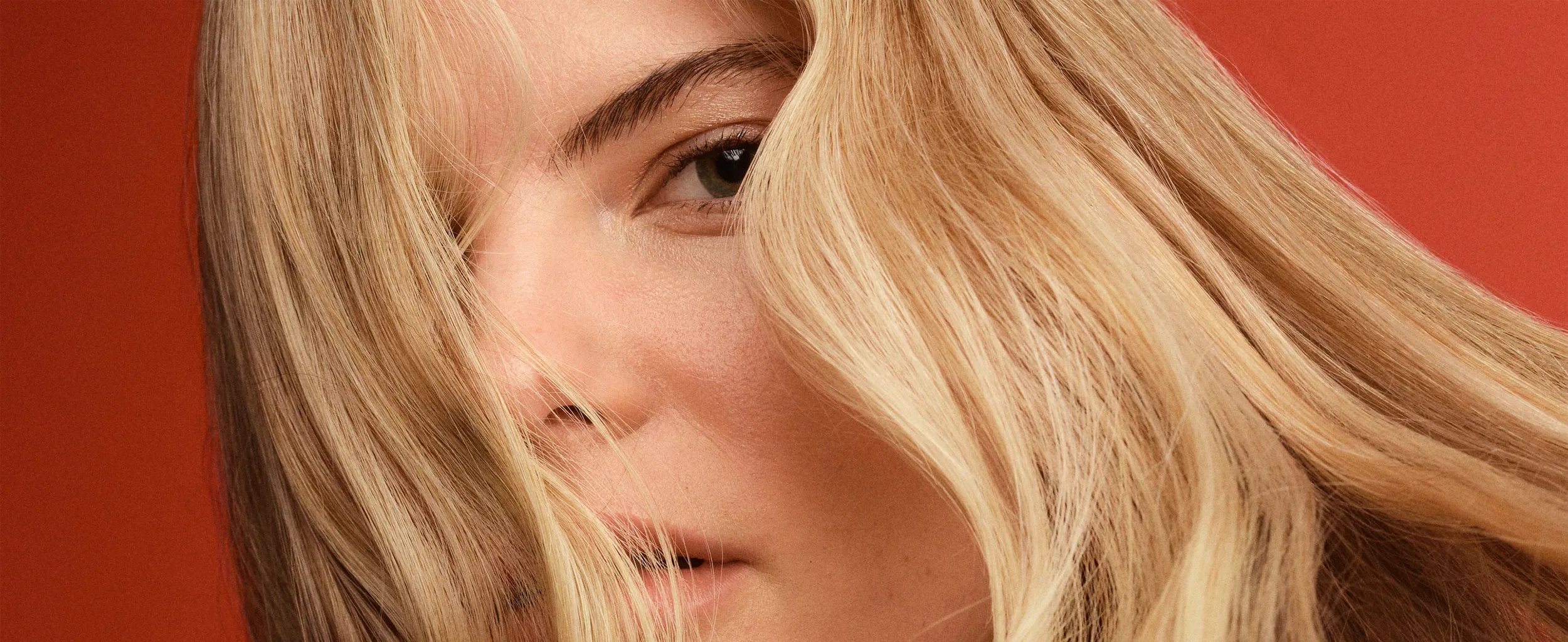 Woman with wavy blonde hair covering part of her face.