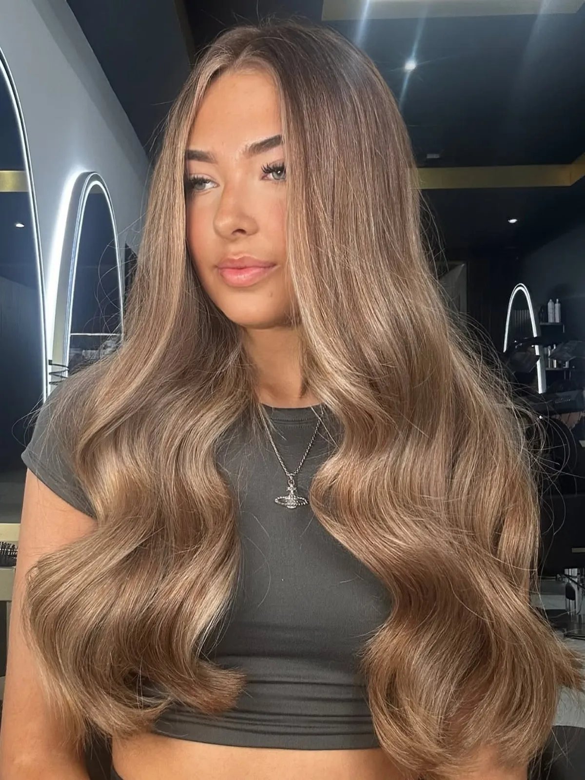 Model with long, loosely curled, dark beige blonde hair.