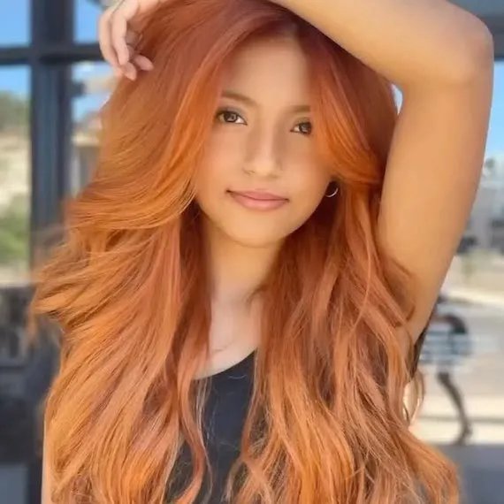 Long, layered hairstyle with loose waves and a vibrant copper-red color