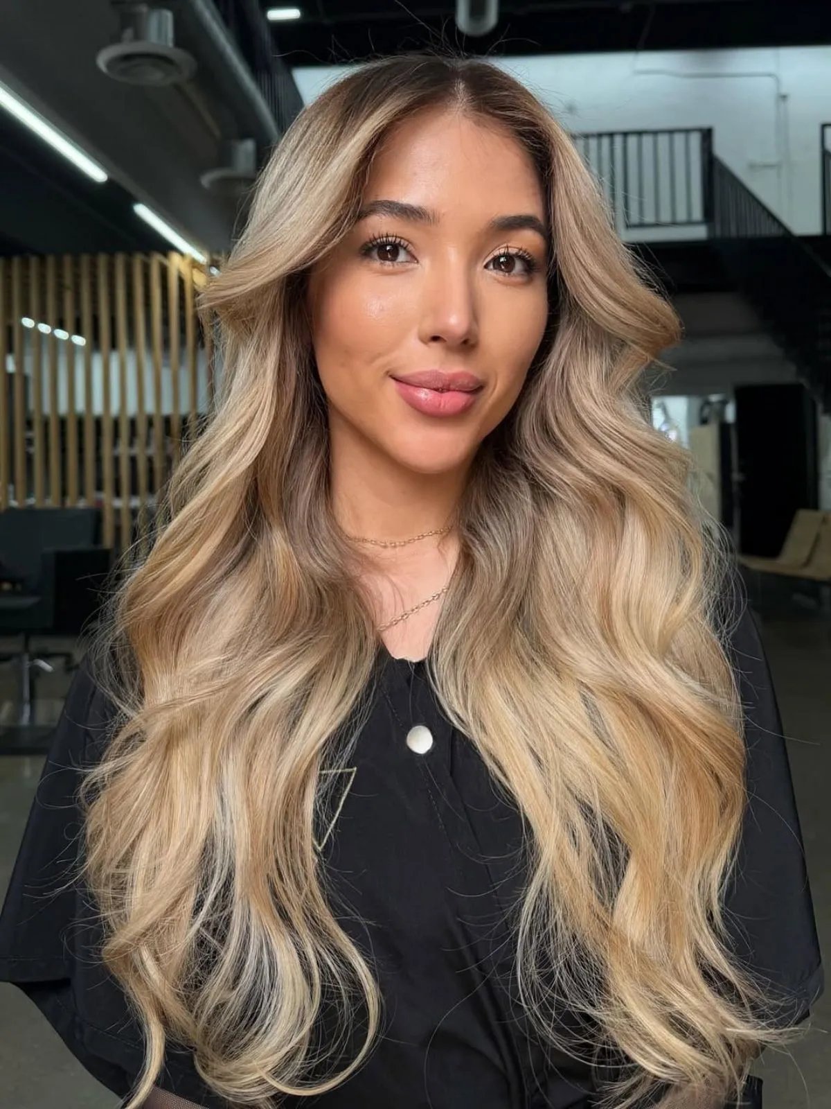 Model with long, loosely curled, buttercream blonde hair.