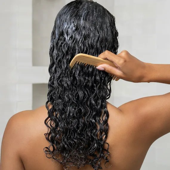 Model combs ULTIMATE SMOOTH Mask through their damp, brown, curly hair.