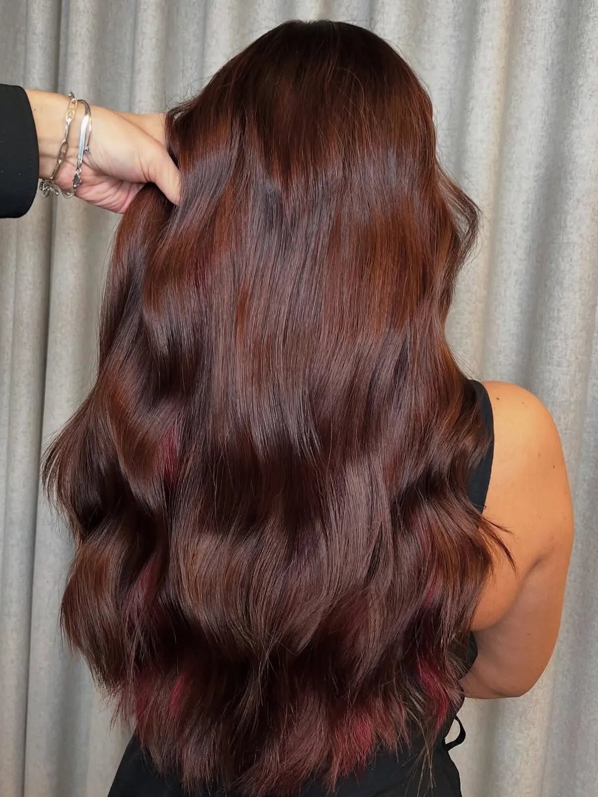 Back of model’s head with long, loosely tousled, maroon hair featuring cherry highlights.