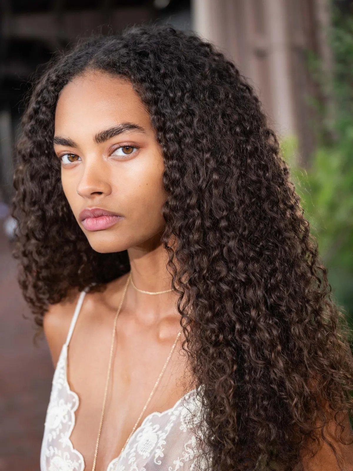 Model with long, dark brown, curly hair wears a lace cami at Ulla Johnson SS27.