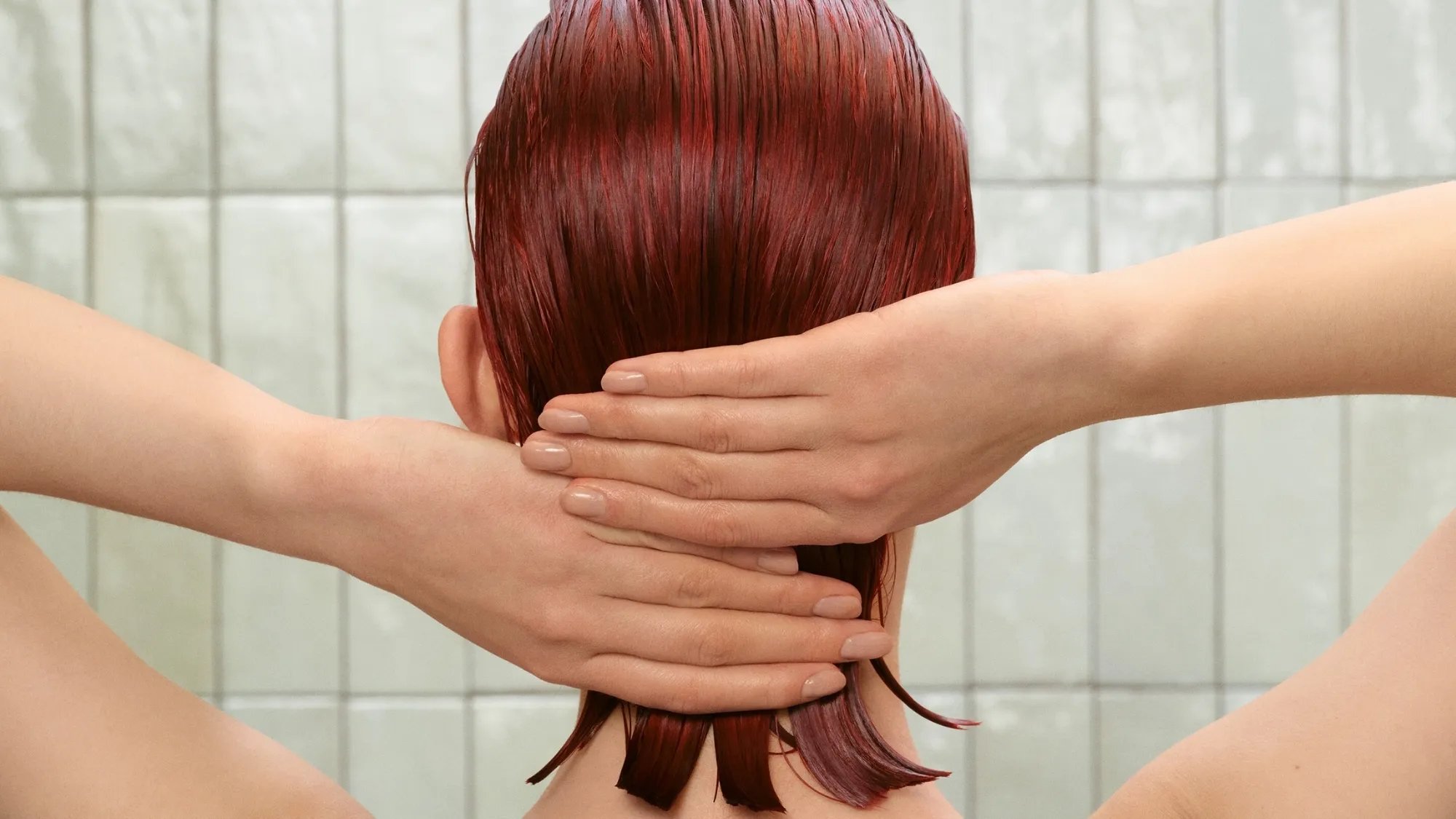 Model smooths hands through red, damp hair.