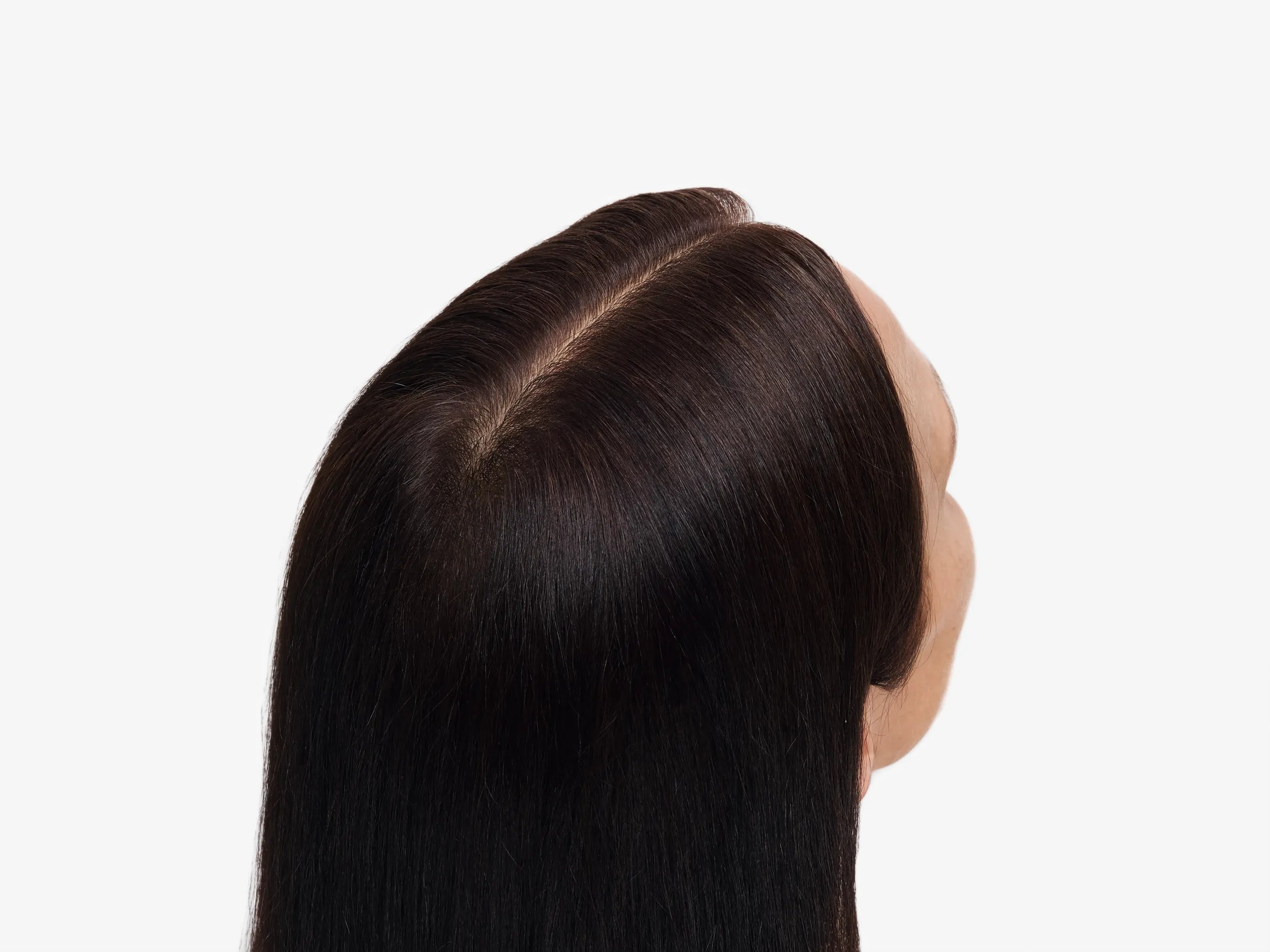 Model with long dark brown hair faces away from the camera. Grey roots shown in the before image are no longer visible.