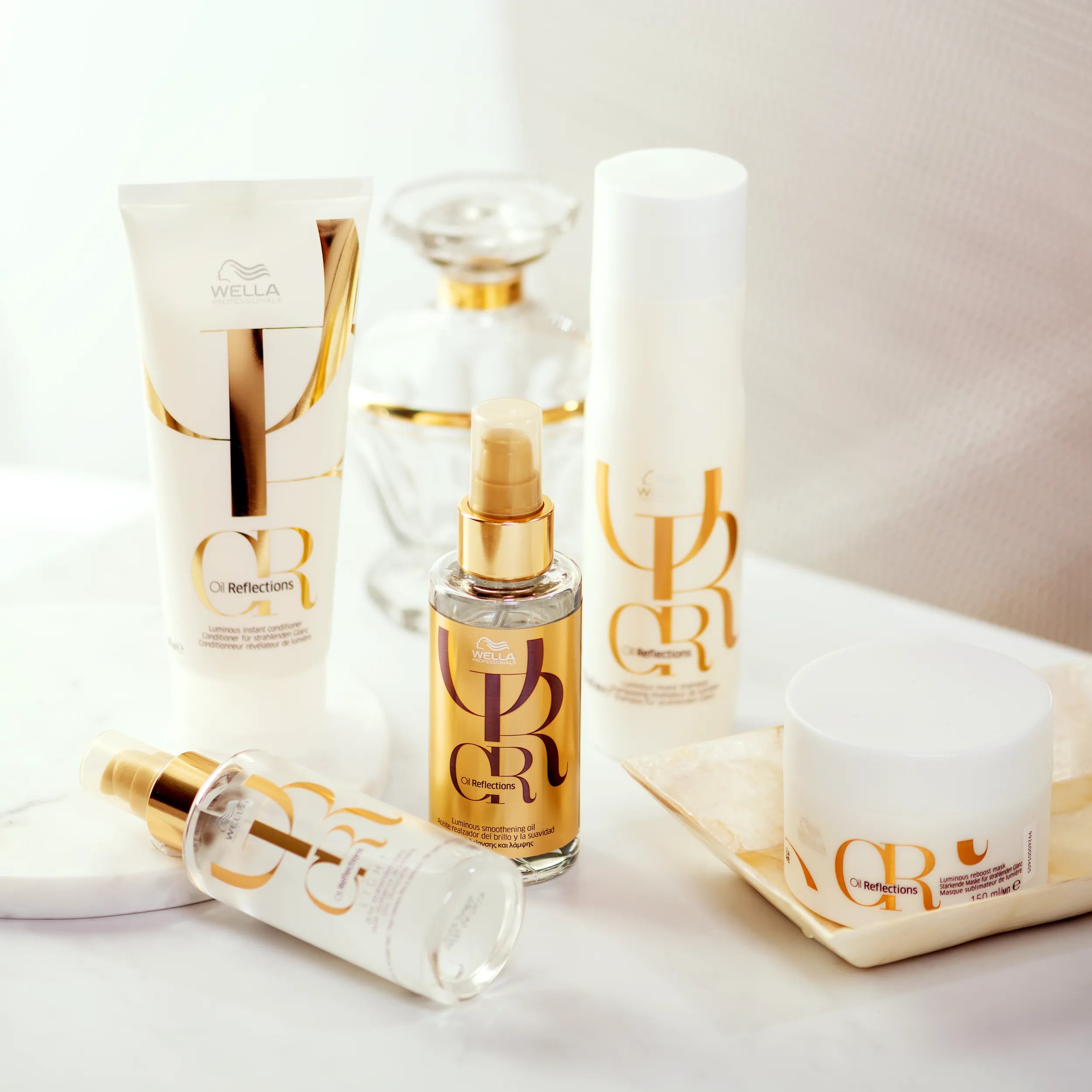 Fotografía de todos los productos de la gama Oil Reflections de Wella Professionals. Incluye el Reveal Shampoo, Instant Conditioner, Smoothing Oil y Reflective Oil.