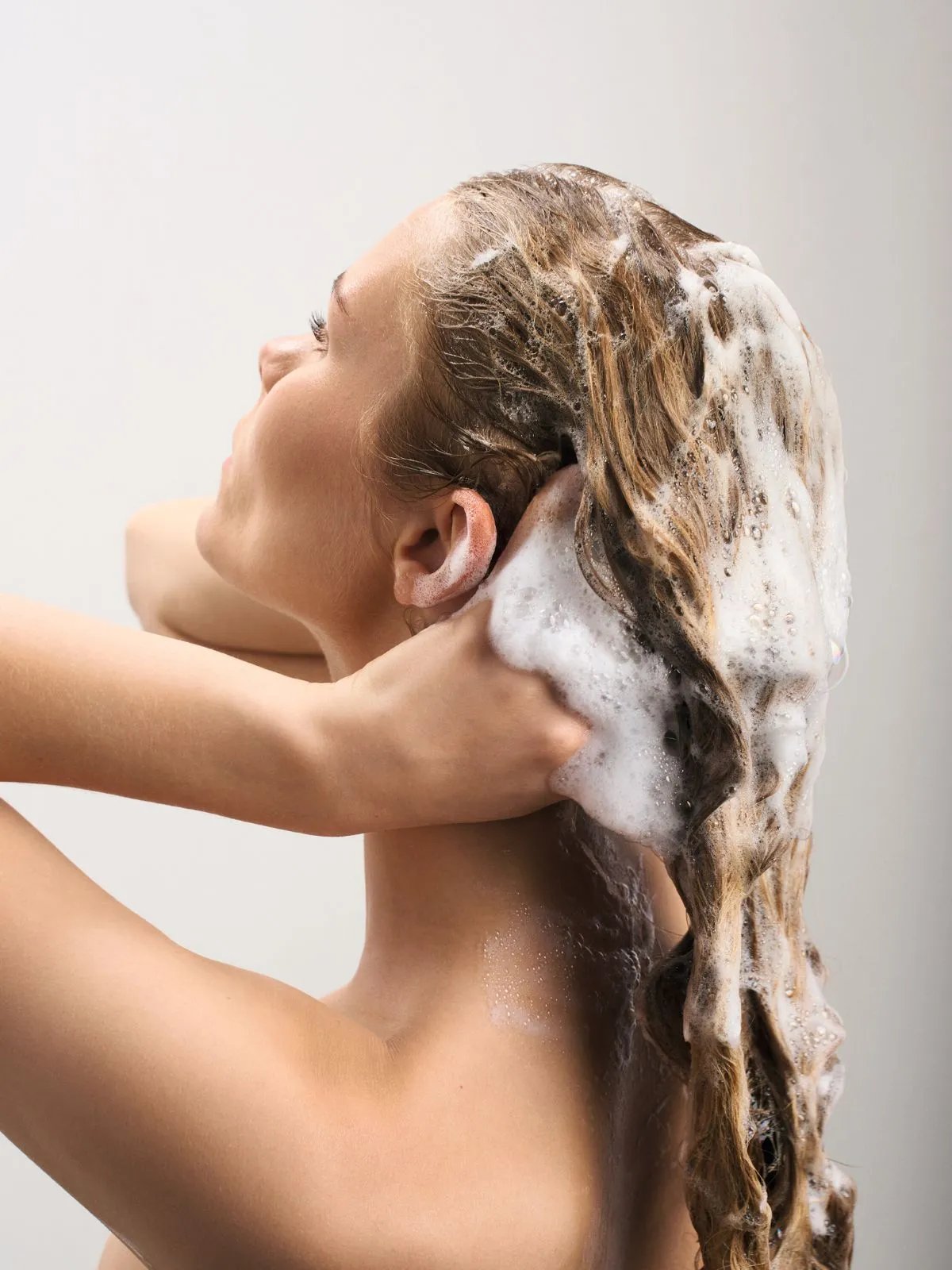 Model massages ULTIMATE SMOOTH Shampoo into wet hair.