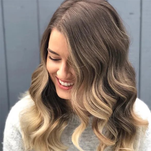 woman with long, wavy, and glossy brown hair featuring warm copper highlights.