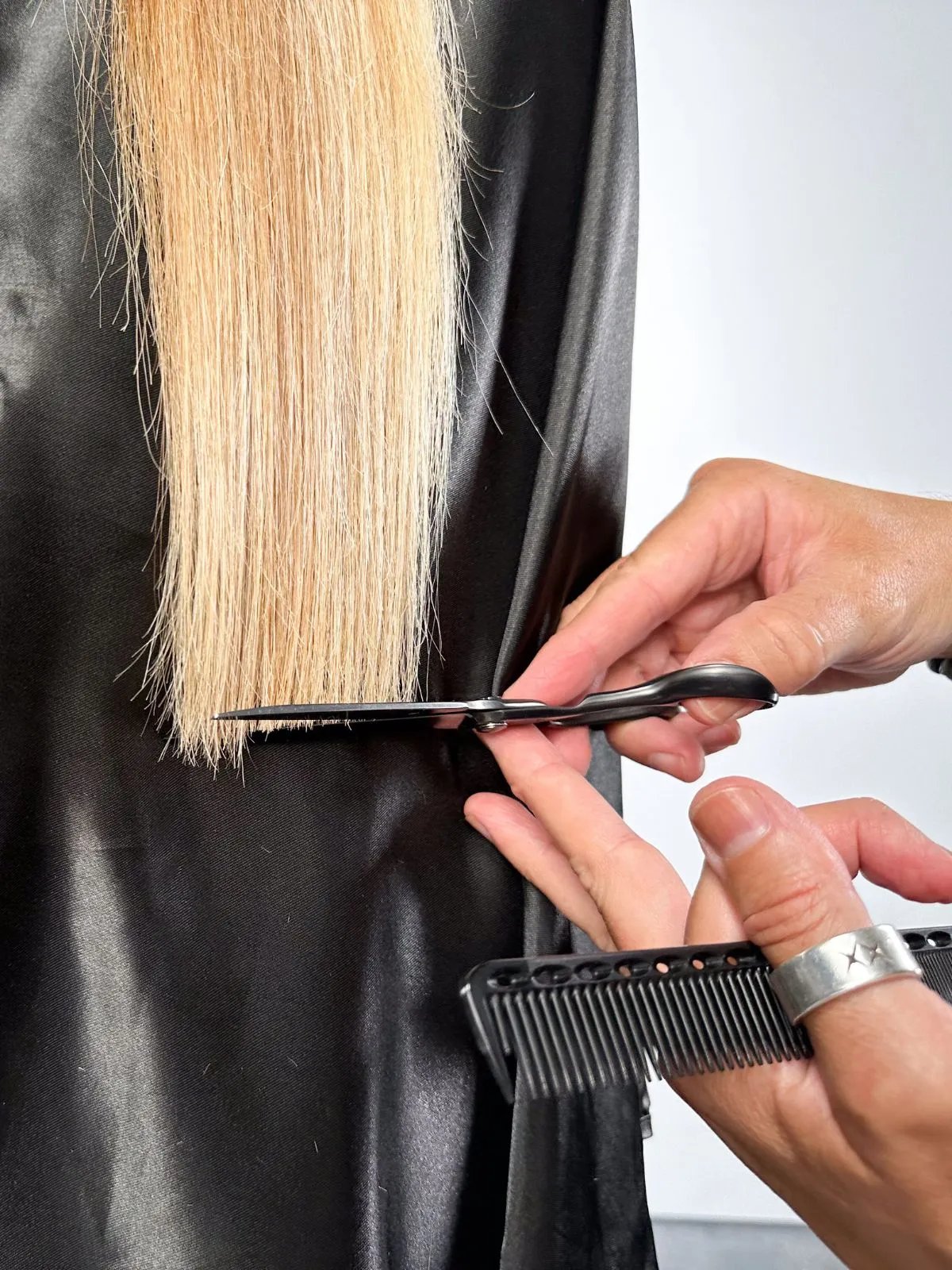 Model’s blonde hair is carefully trimmed by a stylist.