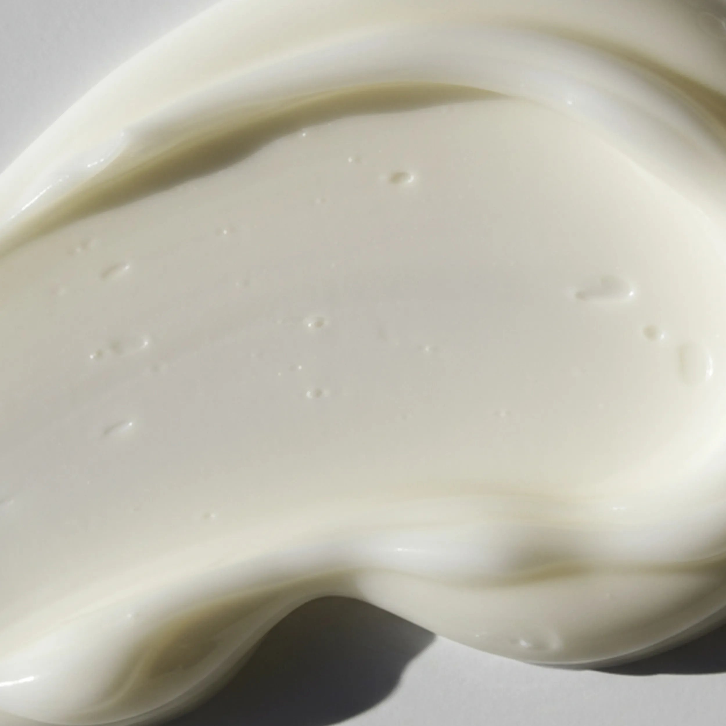 Swirl of white cream against a light-colored background.