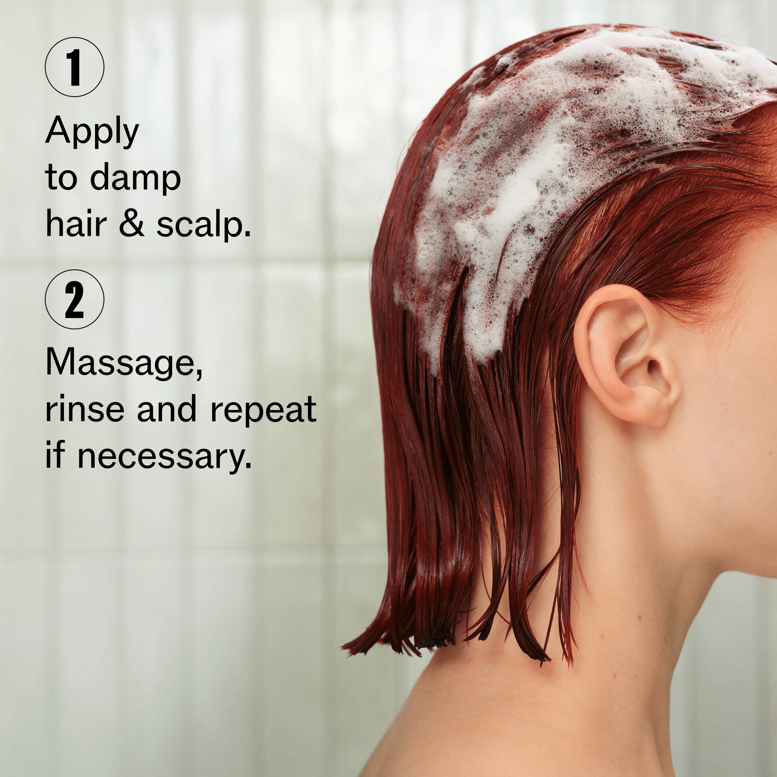 Image of a model's profile, cropped to not show their face. Model's hair is red, short and wet with shampoo foam in it. Text overlay reads "1. Apply to damp hair & scalp. 2. Massage, rinse and repeat if necessary".