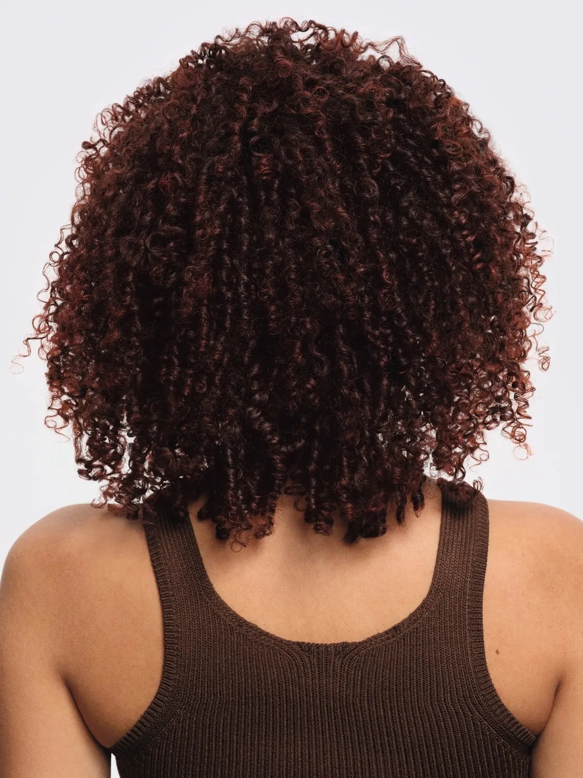 Model with glossy, mahogany red curls after their hair has been colored with Supernatural Color.
