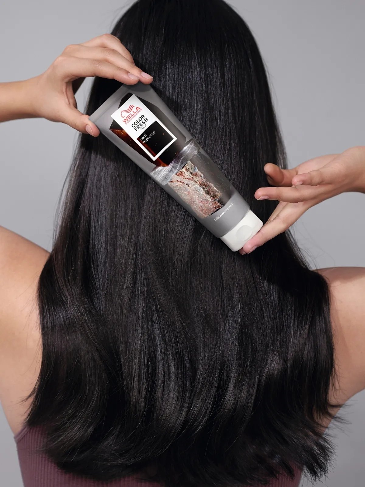 Model with dark brown hair holds a tube of Color Fresh Mask in Cool Espresso.
