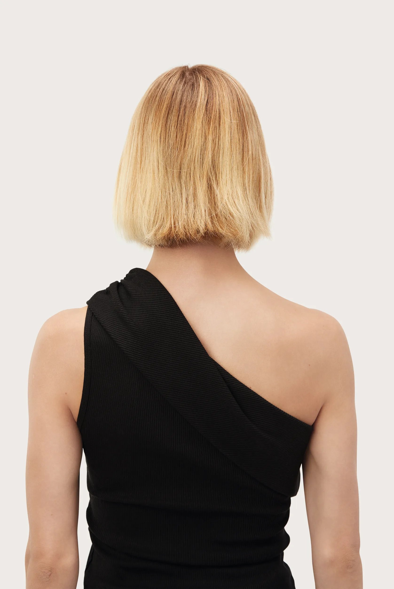 Model with short blonde bob faces away from the camera. Hair looks brassy and dull. 