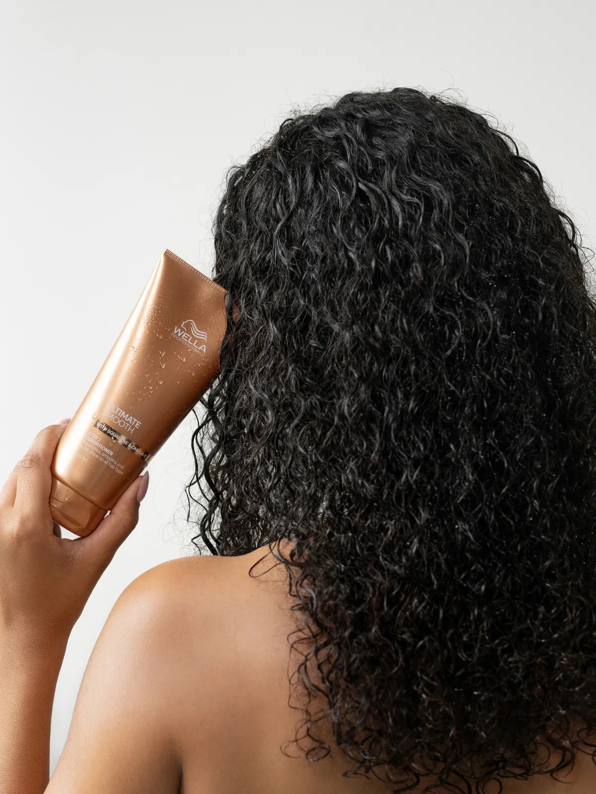 Model holds a bottle of ULTIMATE SMOOTH Conditioner.
