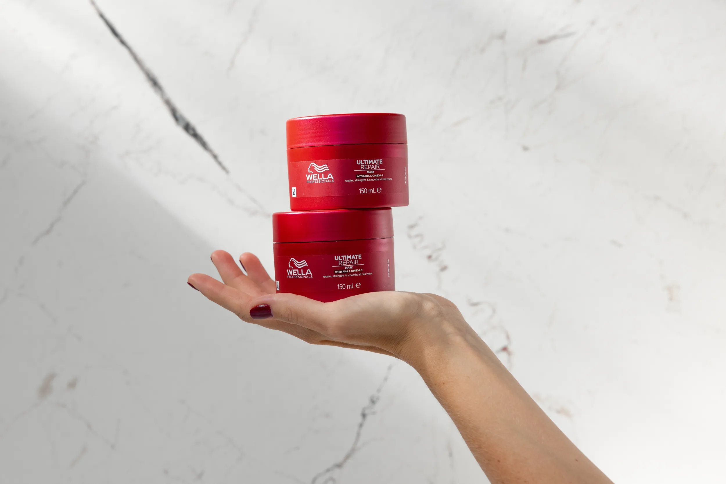 Model with clean, damp hair wrapped in a towel holds up ULTIMATE REPAIR Mask.