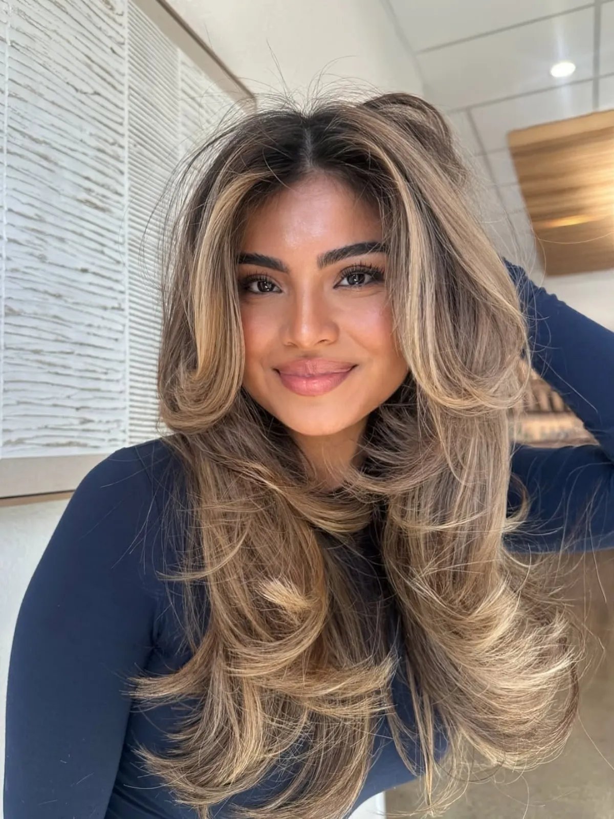 Model with dark brown, voluminous hair featuring beige blonde highlights.