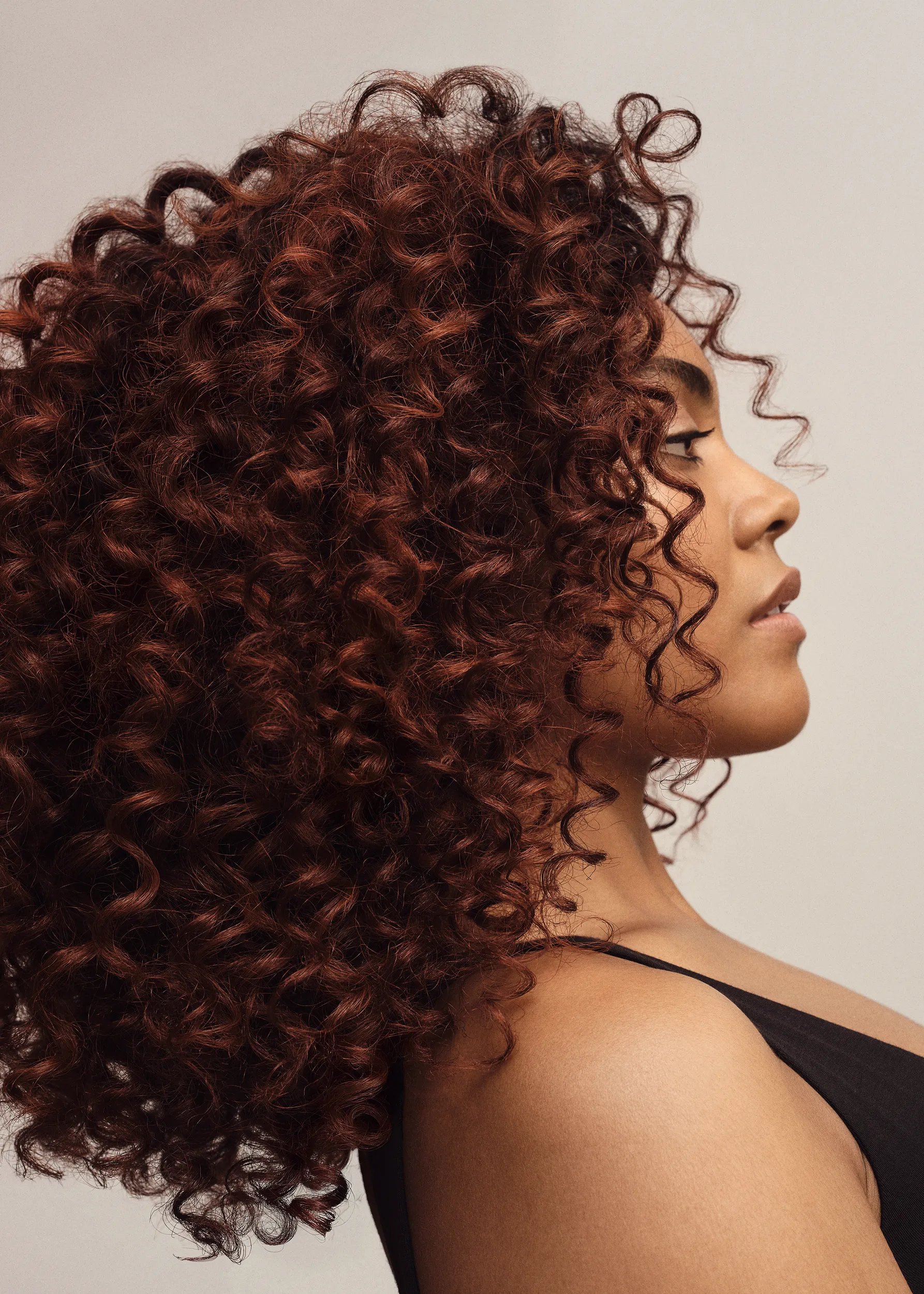 Model with long, curly, dark red hair.