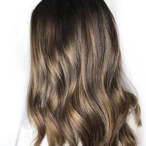 Back of model’s head with long, dark brown, wavy hair.